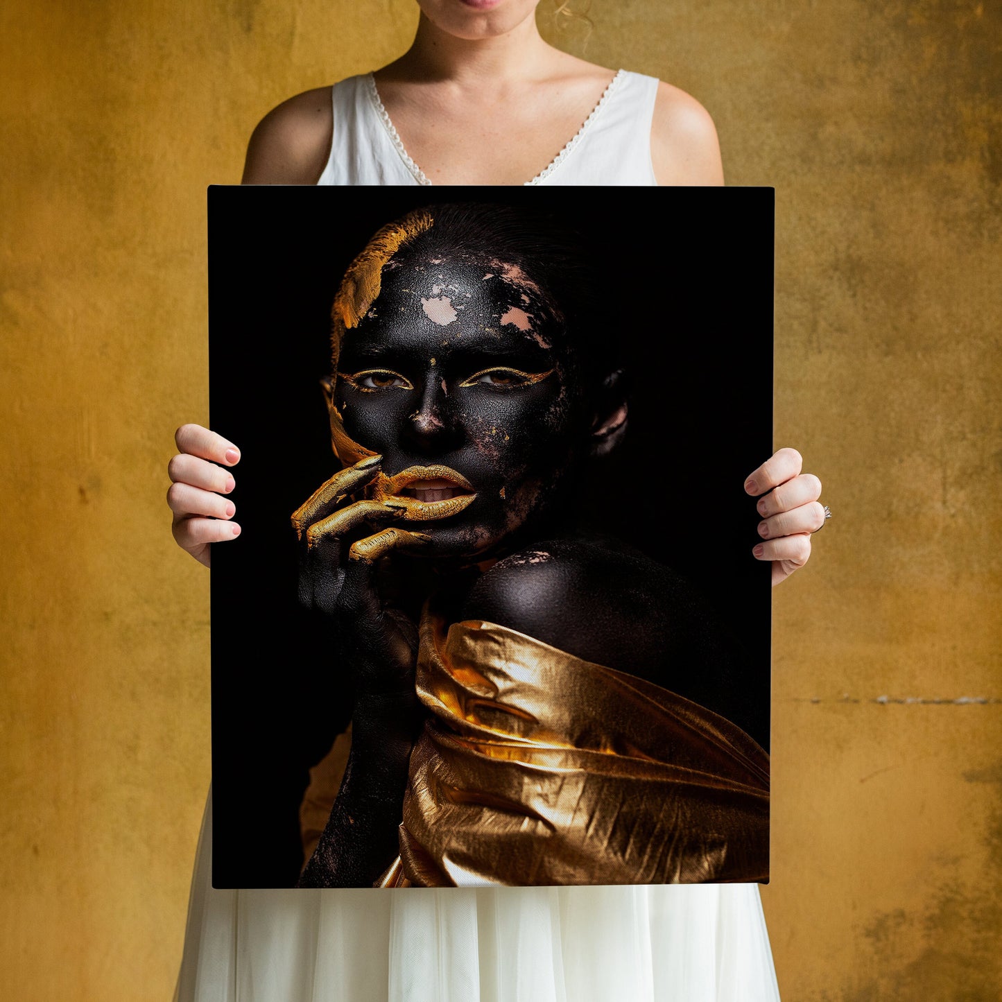 a woman holding up a black and gold painting