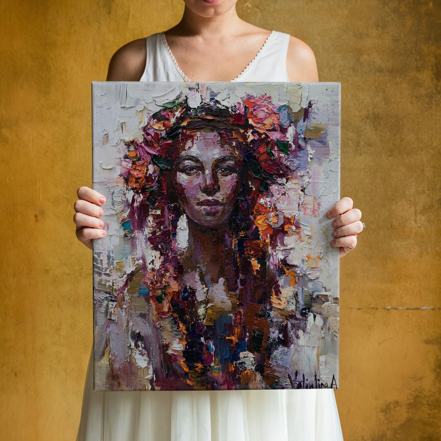 a woman holding up a painting of a woman with flowers in her hair
