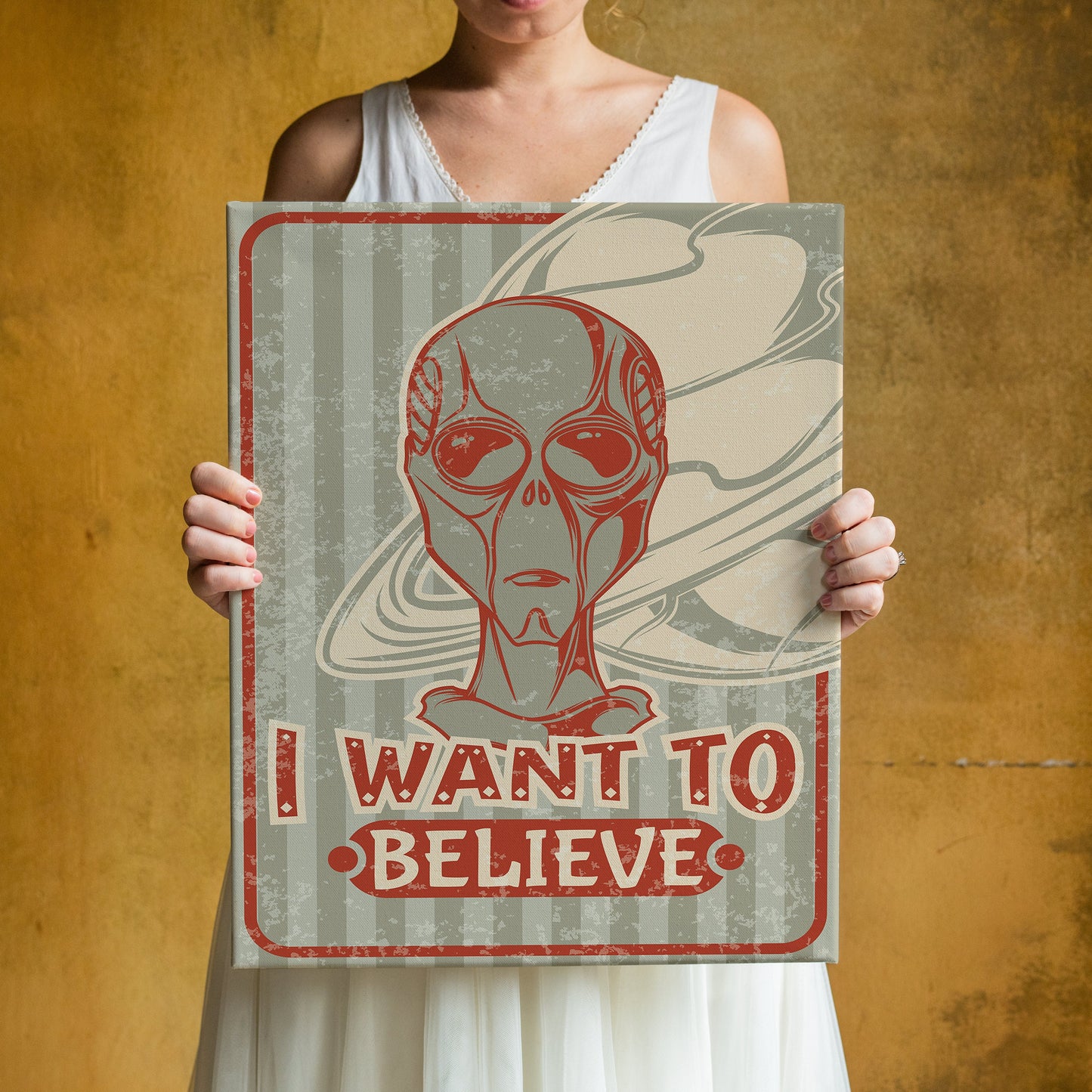 a woman holding up a poster with a picture of an alien on it